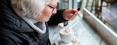 An older woman enjoying a sugary coffee with whipped cream