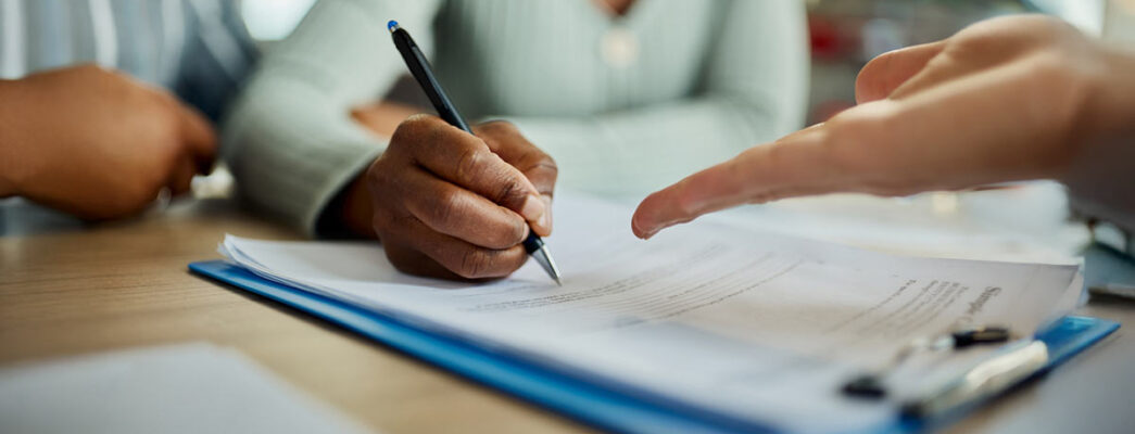 Closeup of people signing documents at a table