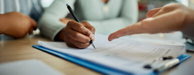 Closeup of people signing documents at a table