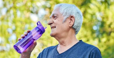 Older man outside holding a plastic bottle filled with water