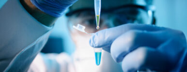 A lab technical uses a dropper to add liquid to a test vial