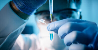 A lab technical uses a dropper to add liquid to a test vial