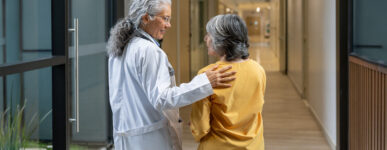 Doctor walking down a hall talking to an older female patient