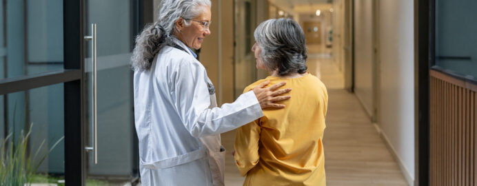Doctor walking down a hall talking to an older female patient